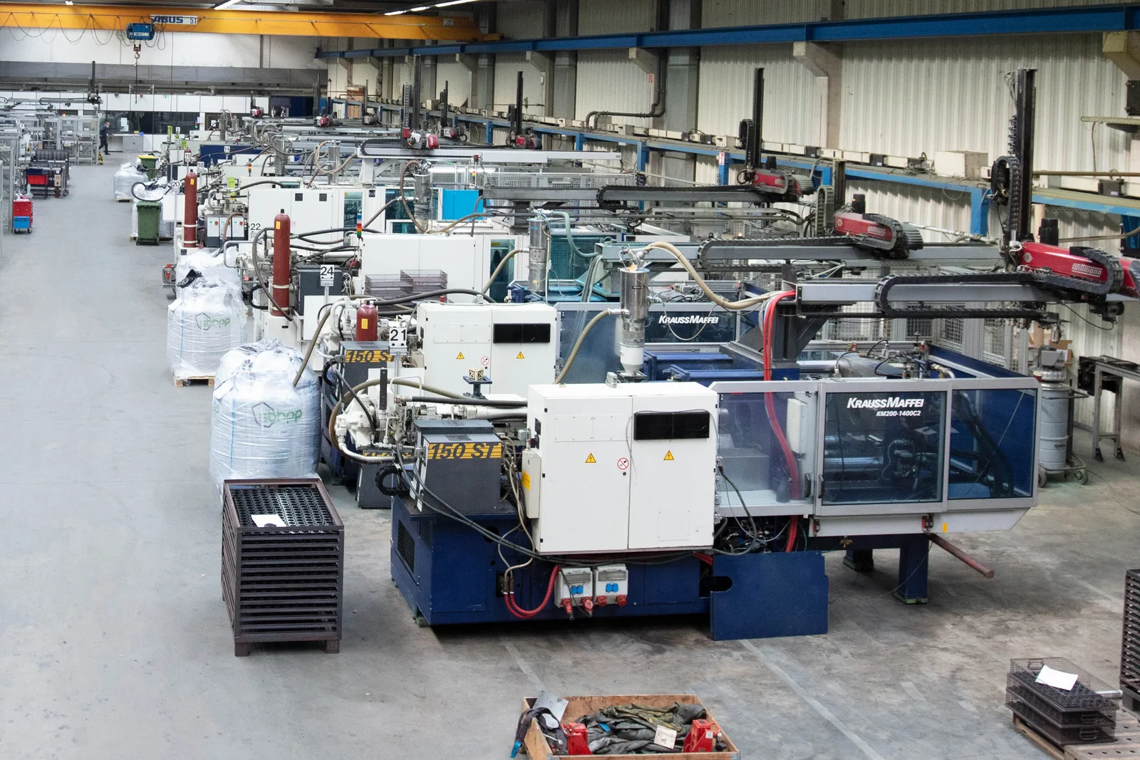 Produktionshalle mit Reihen vollautomatisierter Duroplast-Spritzgießzellen und Linearrobotern